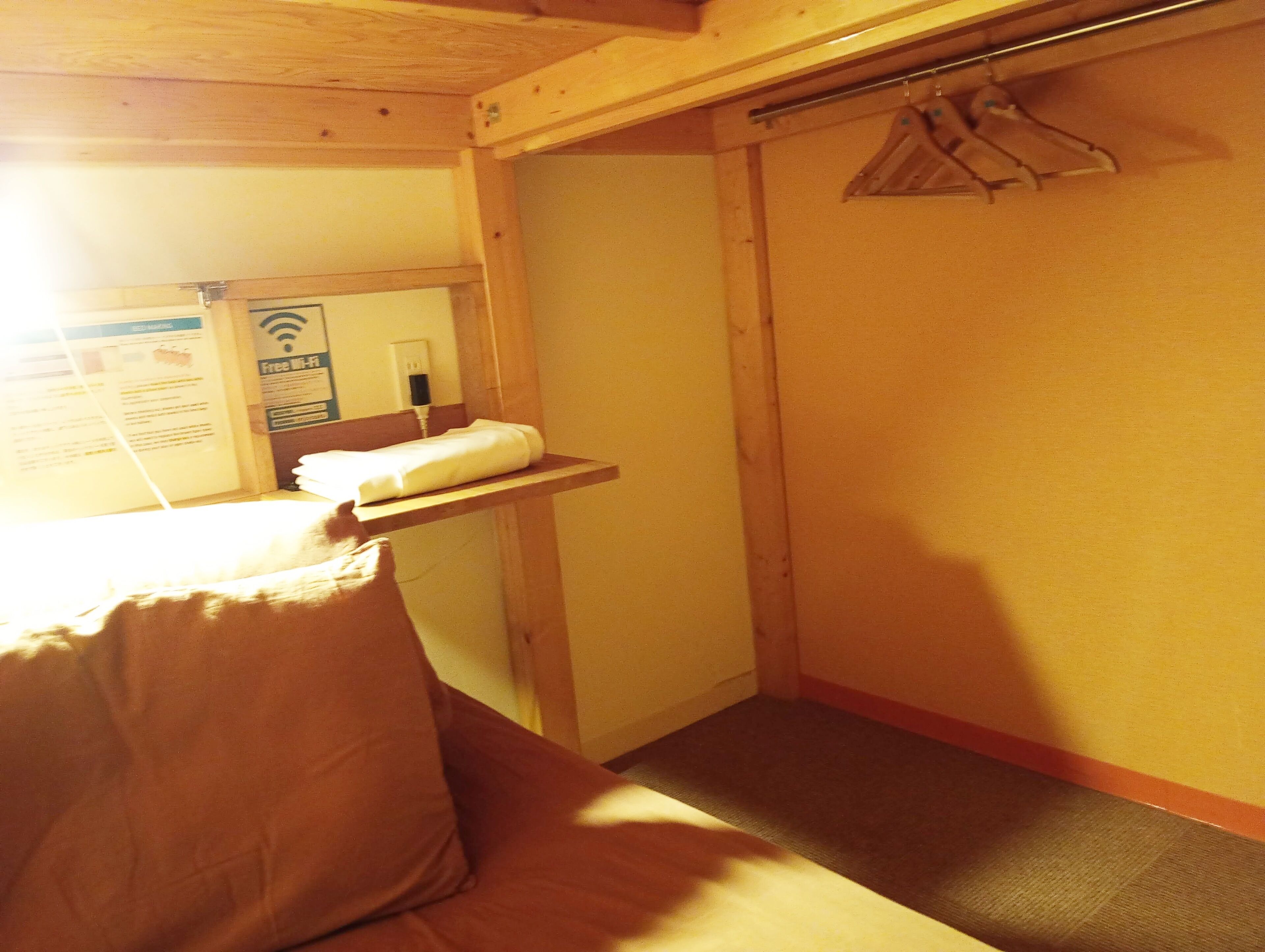 Una habitación pequeña y funcional con cama, banco y perchero.