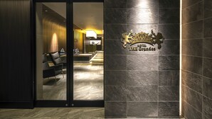 A hotel lobby with a reception desk, seating area, and a logo on the wall.