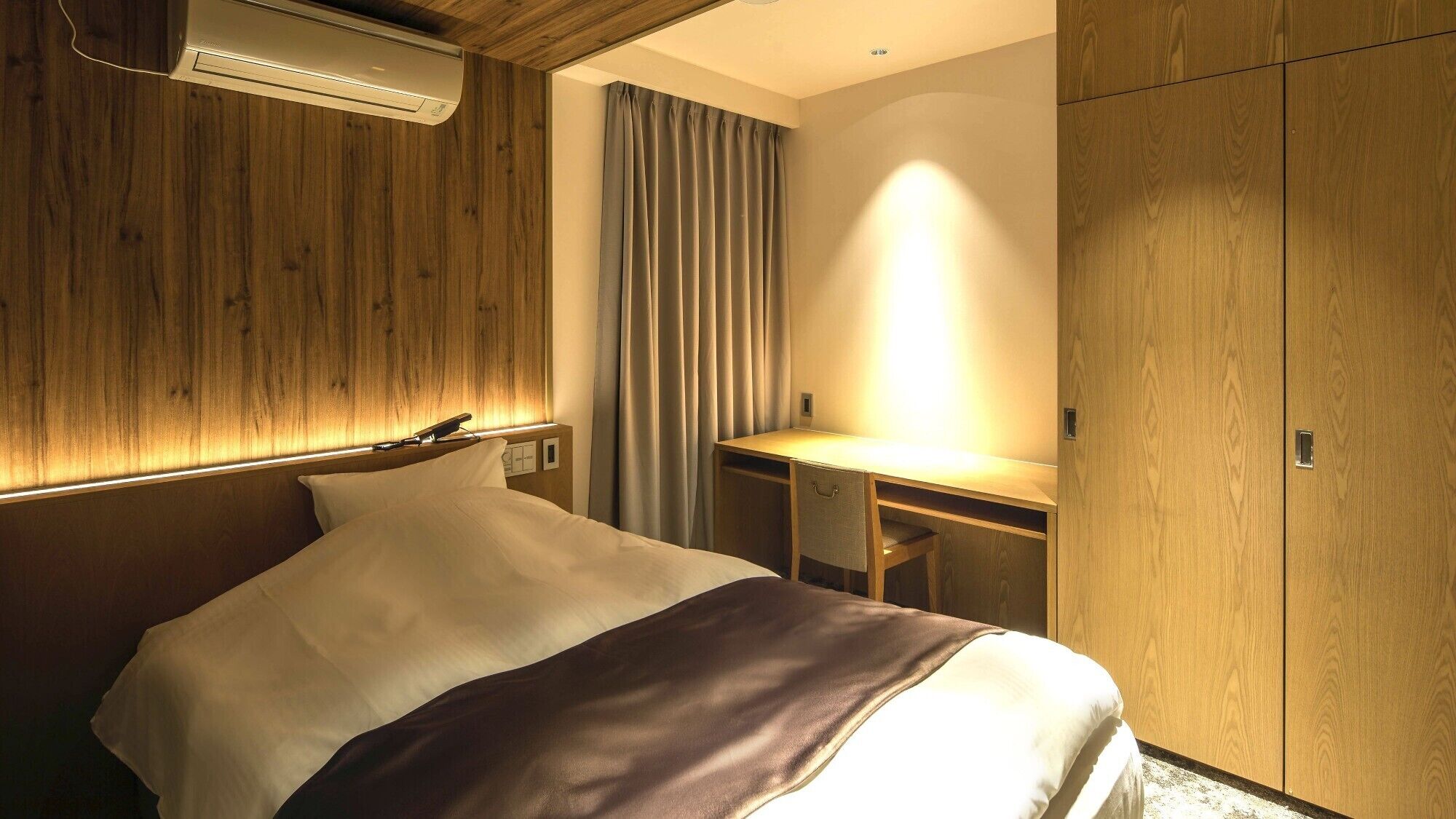 Una habitación de hotel con una cama, un escritorio y un armario.