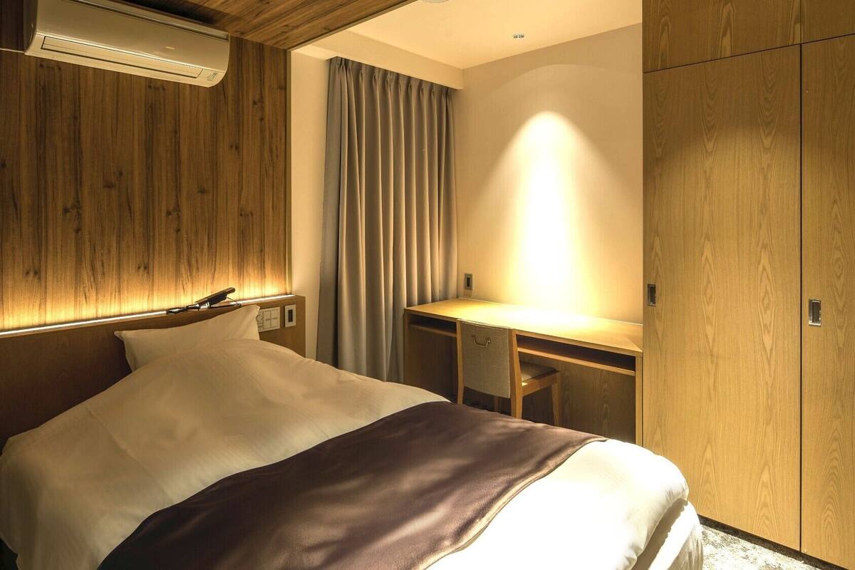 Une chambre d’hôtel avec un lit, un bureau et une armoire.