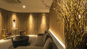 A modern lounge area with a sofa, chairs, a round table, and a decorative plant.