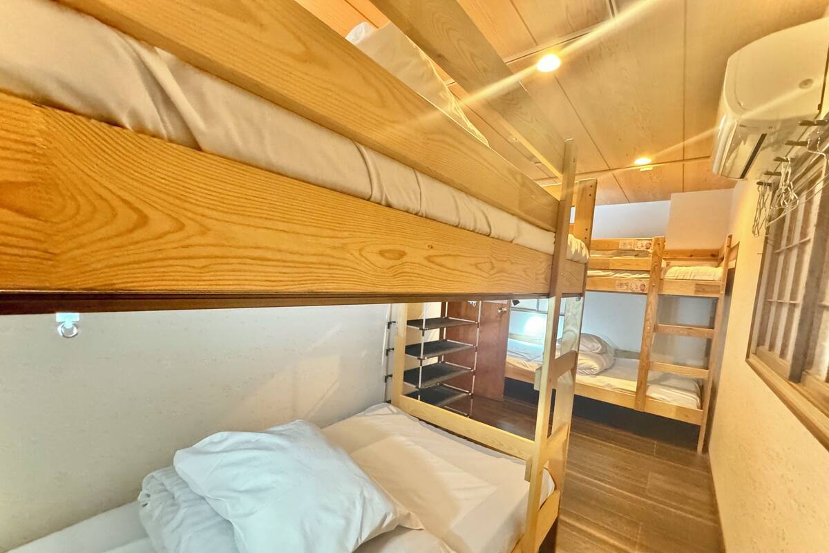 A bunk bed room with a wooden ceiling and a window.