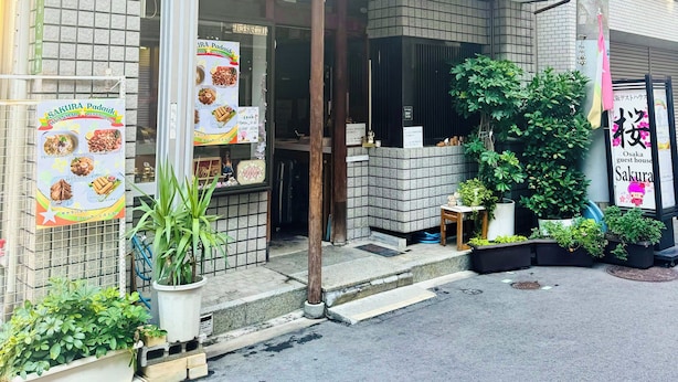 A building with a sign reading "Sakura Guest House" and a no parking sign.