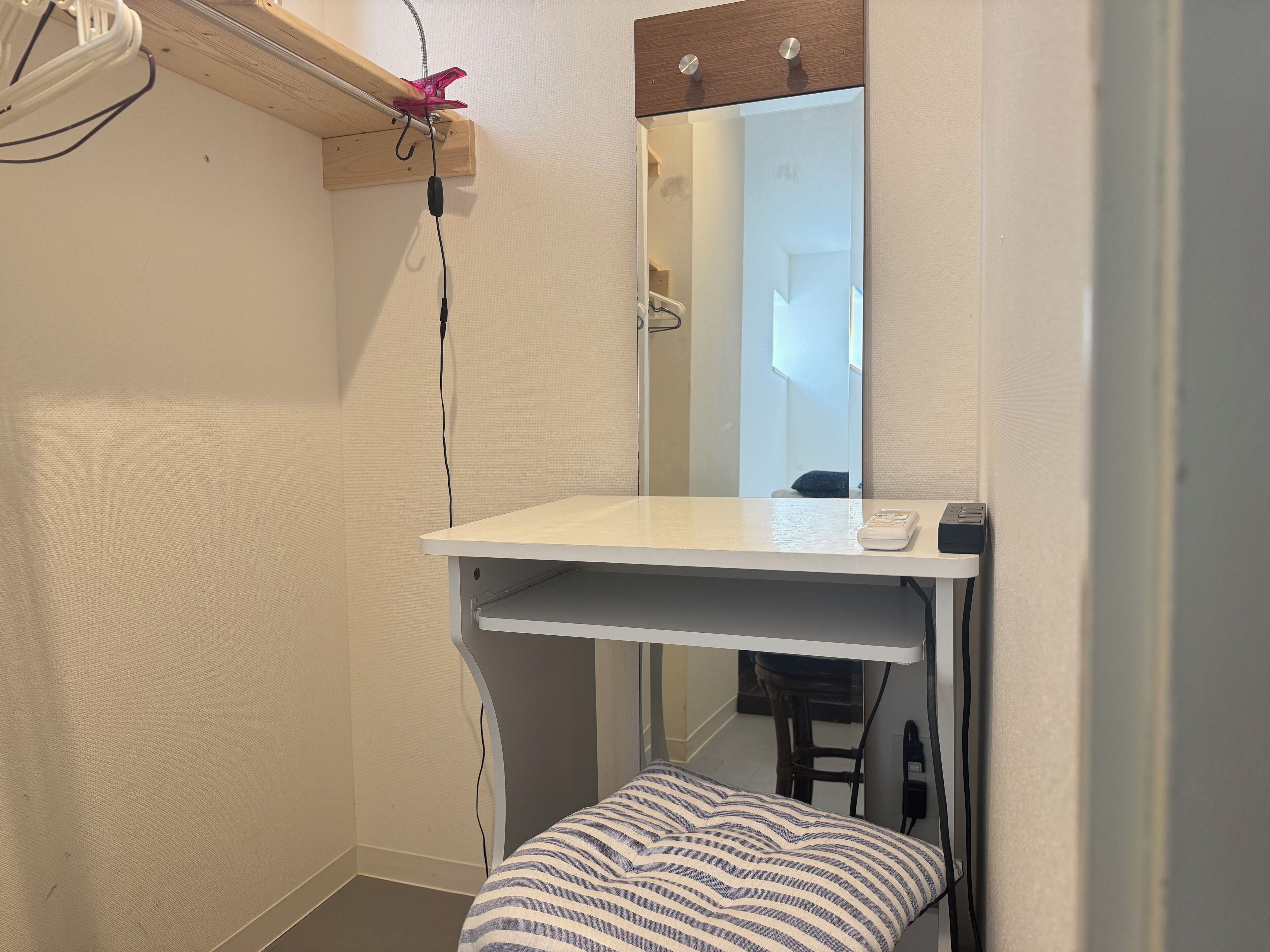 A small, compact bathroom with a white countertop, a mirror, and a striped bench.