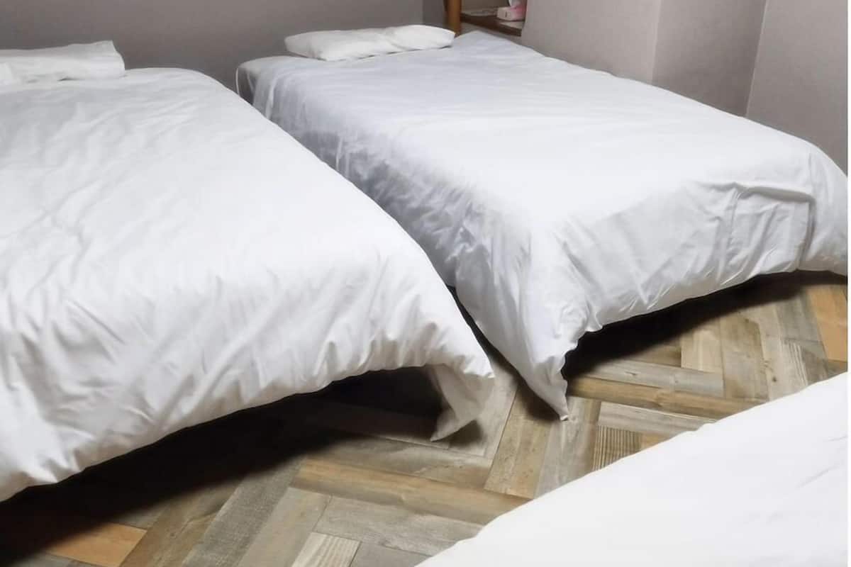 A room with two beds, a wooden herringbone floor, and a mirror on the wall.