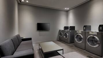 A modern laundry room with a sofa, a table, and a washing machine.