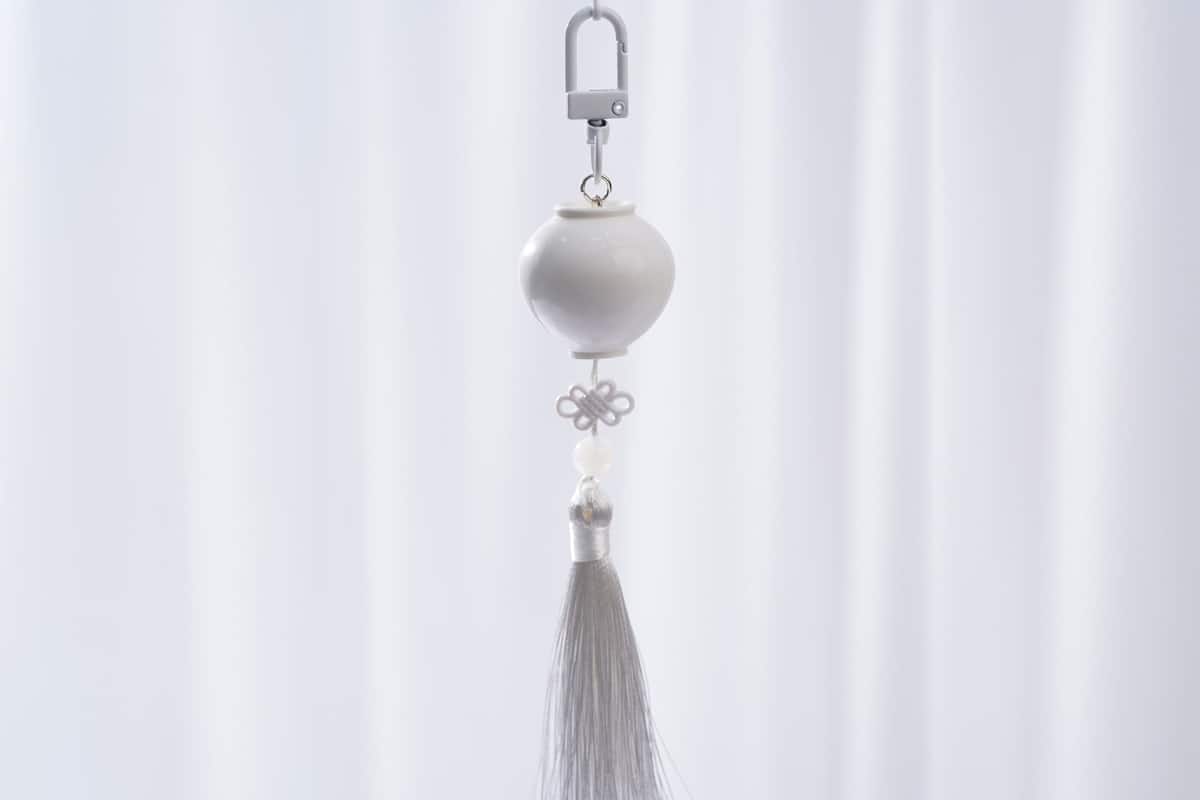A white tassel hanging from a keychain.