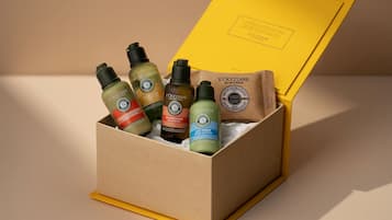 A cardboard box containing L'OCCITANE products, including shampoo, conditioner, shower gel, and body lotion.