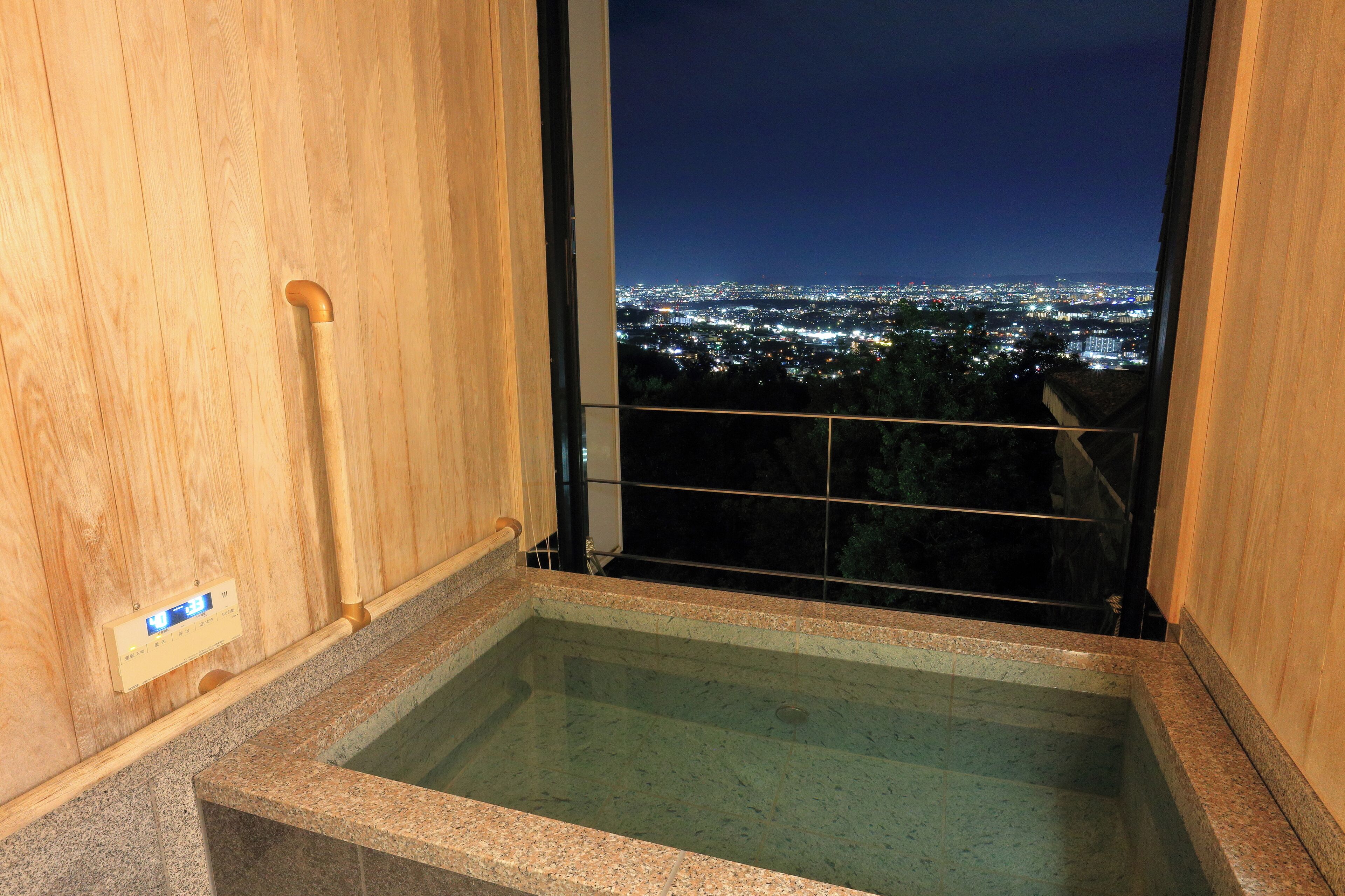 A wooden sauna with a view of a cityscape at night.