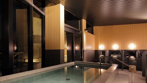 Een modern binnenzwembad met glazen afscheiding, houten lambrisering en ingebouwde verlichting.