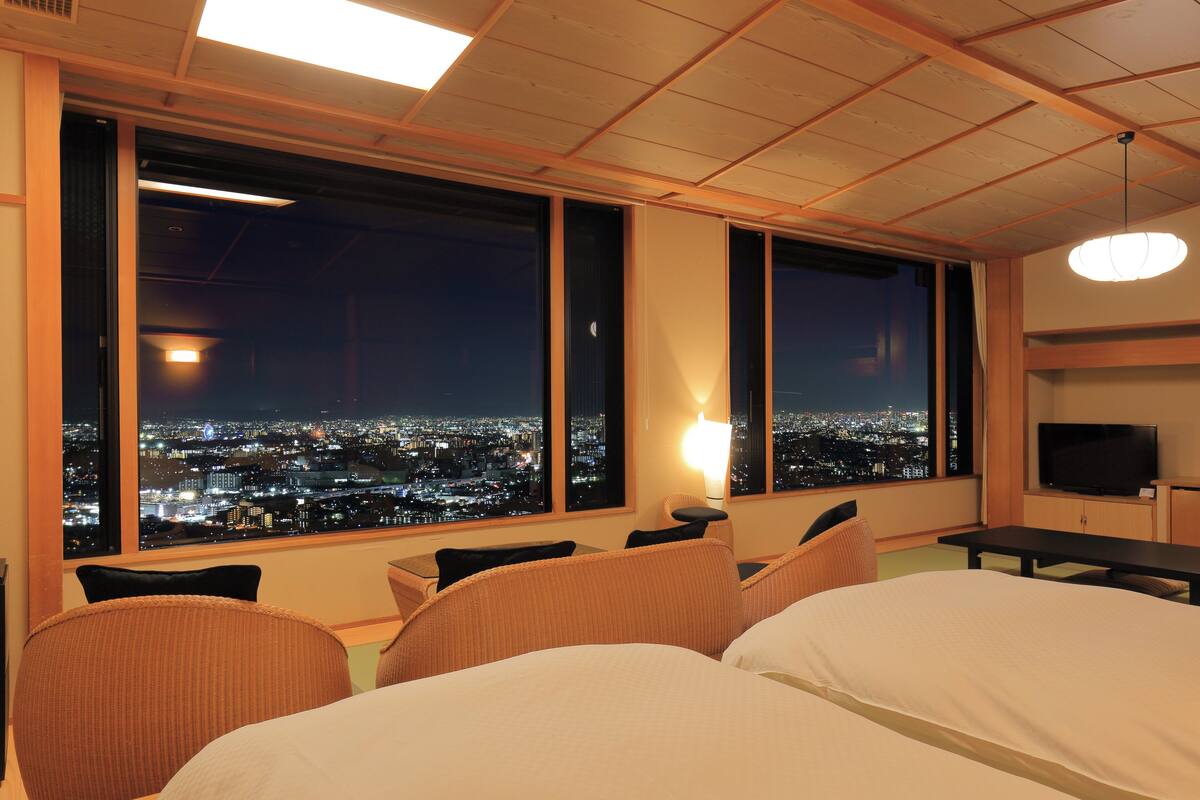 Een hotelkamer met uitzicht op de stad, een bed, een bureau en een televisie.