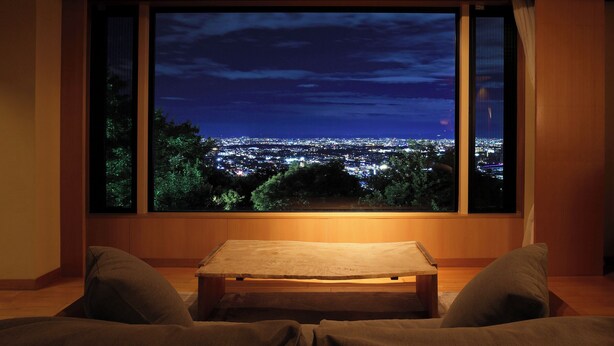 Een kamer met een groot raam met uitzicht op een stadsbeeld bij nacht.
