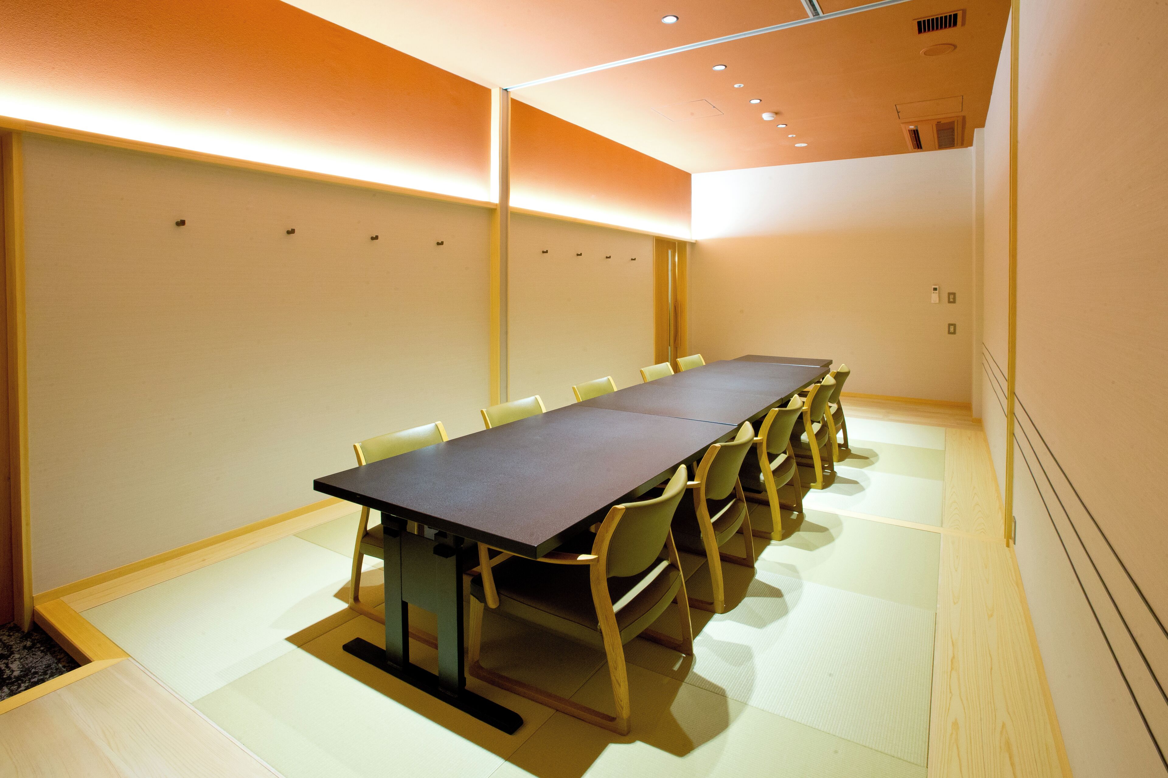 A conference room with a long table, chairs, and a carpeted floor.