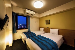 A hotel room with two beds, a window with a view of the city, an air conditioning unit, a wall-mounted TV, and a lamp.