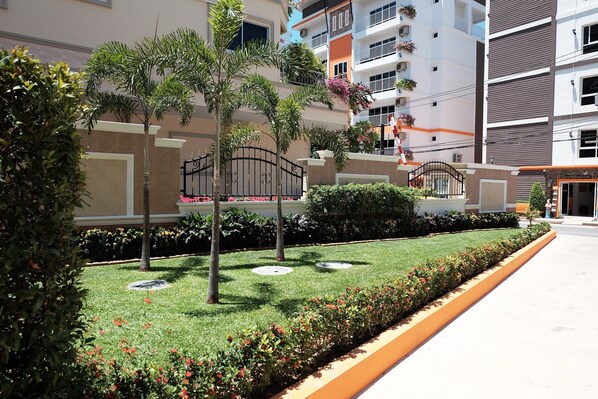 Un immeuble résidentiel doté d’une pelouse bien entretenue, d’une entrée sécurisée et de balcons agrémentés de plantes.
