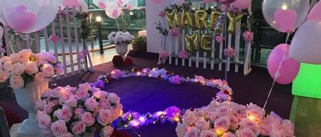 A decorated outdoor event space with a circular floral arrangement, white picket fence, and balloons.
