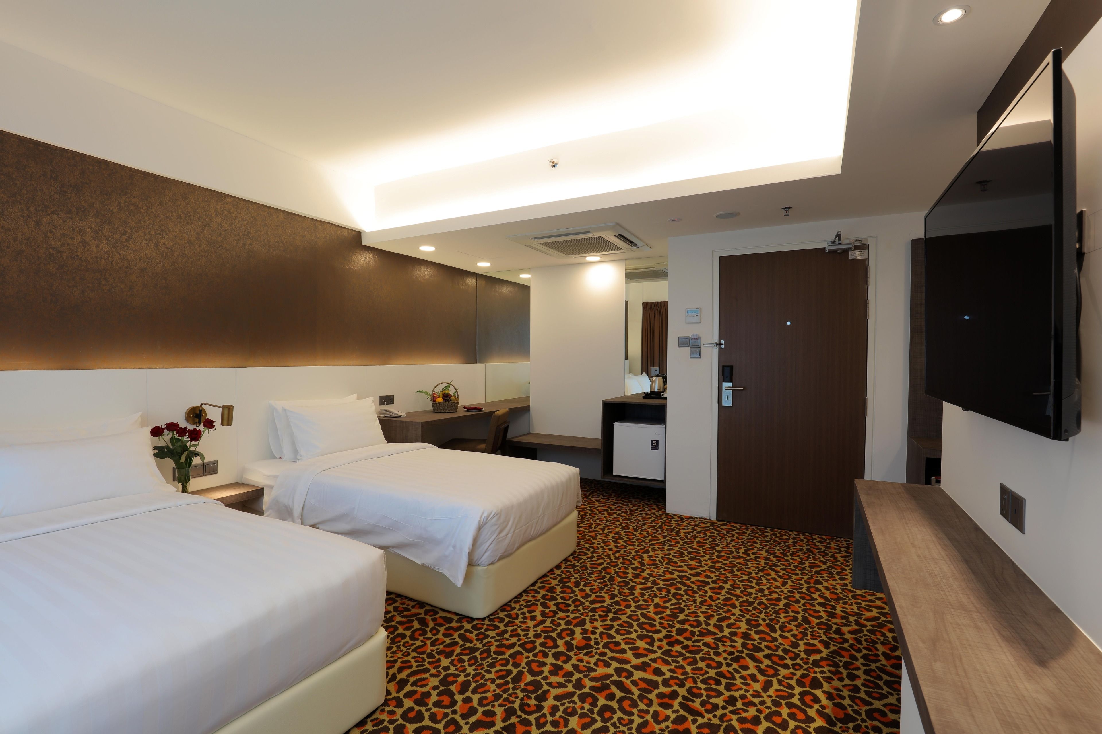Een hotelkamer met twee bedden, een bureau, een spiegel en een televisie.
