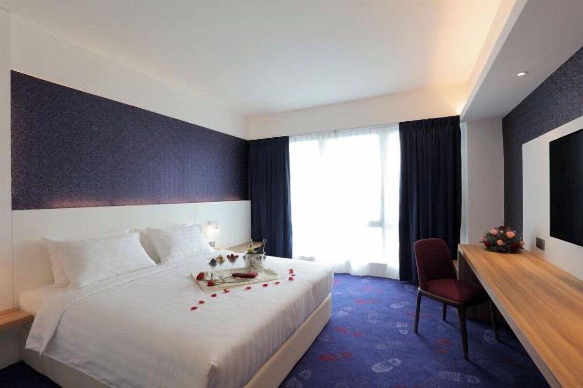 Une chambre d’hôtel avec un grand lit, un bureau et une chaise.