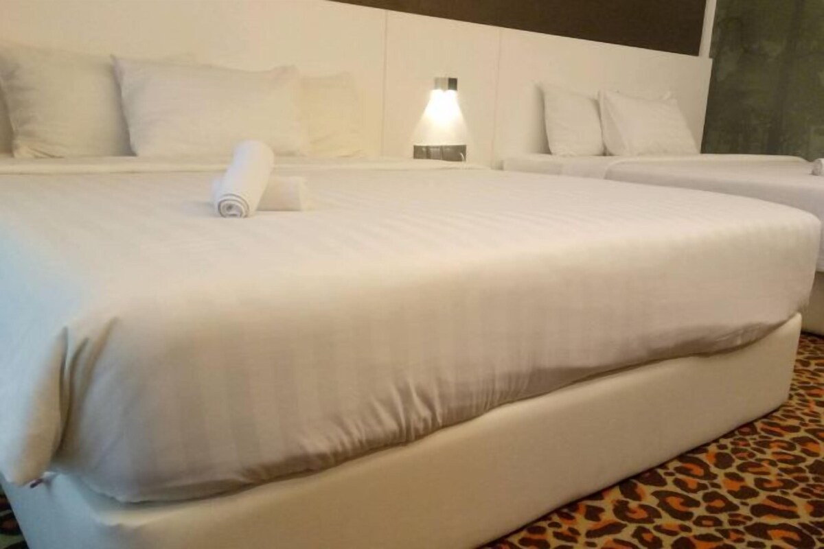 Una habitación de hotel con una cama grande, dos camas más pequeñas y una alfombra estampada.