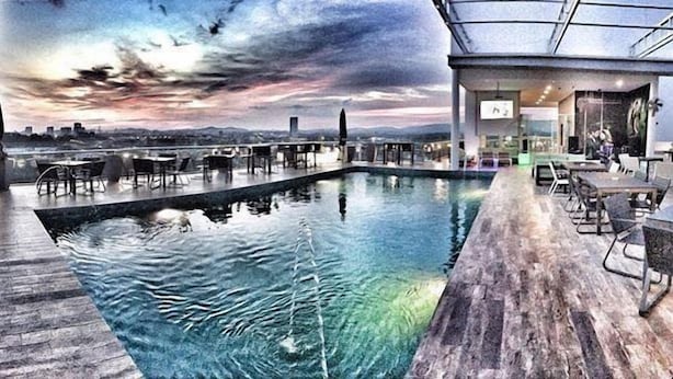 Une piscine sur le toit, offrant une vue sur les gratte-ciel de la ville au coucher du soleil.