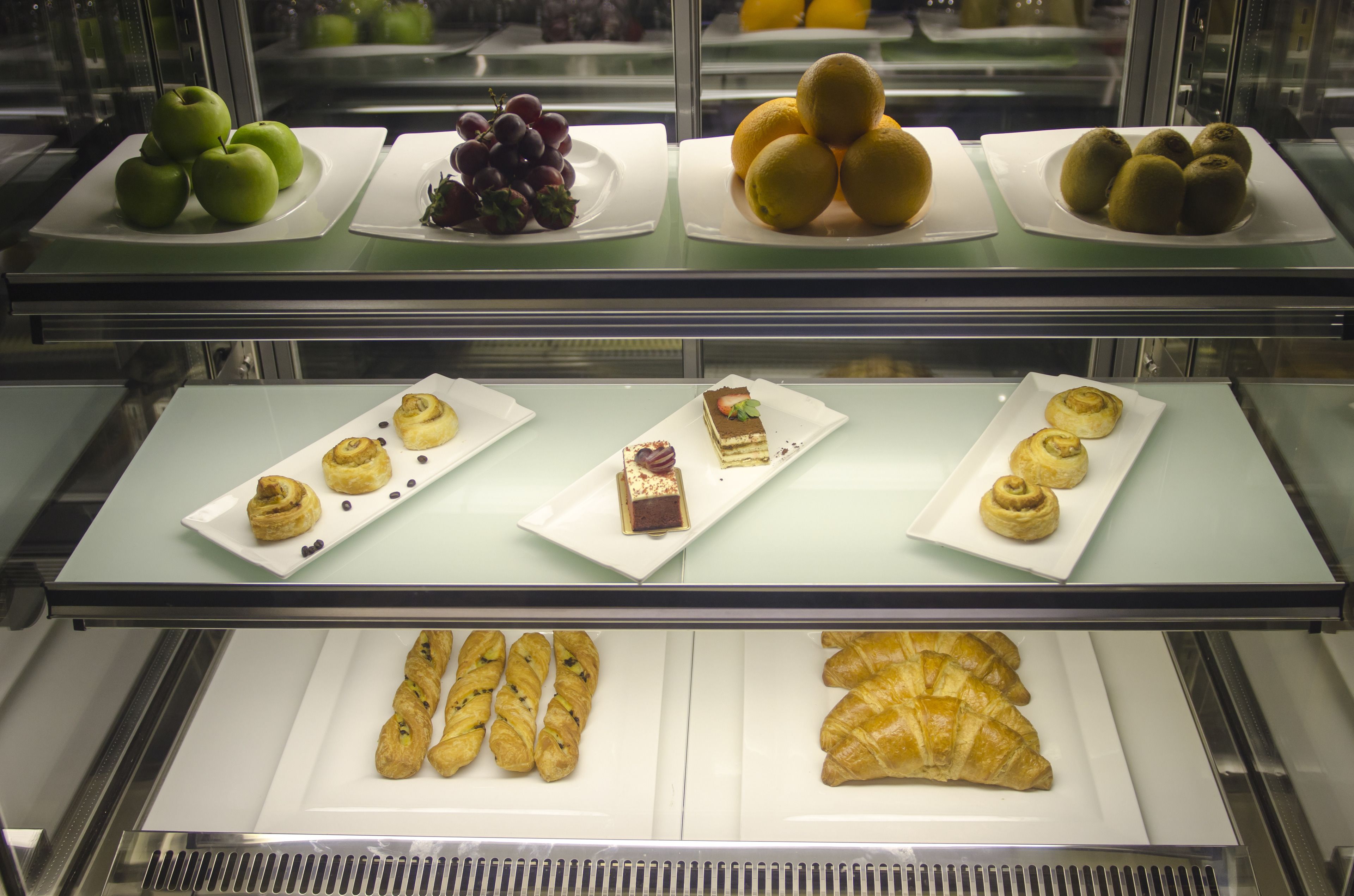 Une vitrine de boulangerie présentant diverses pâtisseries et des fruits.