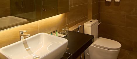 A modern bathroom with a large mirror, a white sink, a black countertop, a toilet, and a glass-enclosed shower.