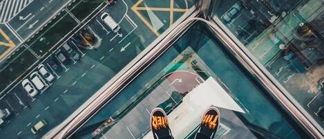 Vista panorámica desde un punto elevado de una ciudad, con piso de vidrio que refleja las calles y los vehículos de abajo.