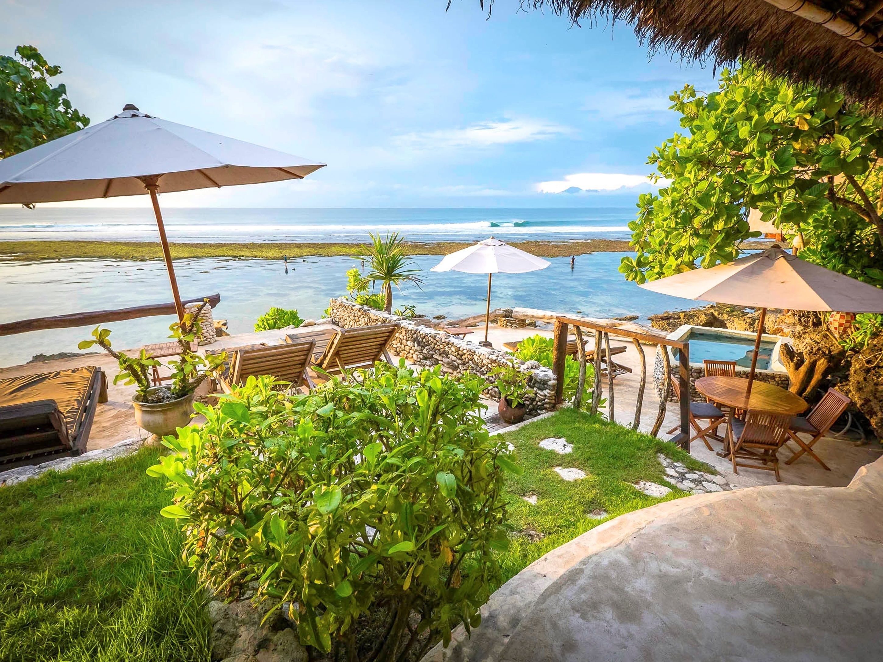 Un patio con mobiliario exterior, sombrillas y vista al mar.