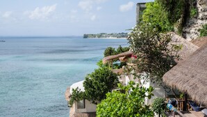 A coastal resort with a pool area, lounge chairs, and a view of the sea. - Rock 'n Reef Hotel (Pecatu)