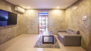 Een moderne woonkamer met een flatscreen televisie, een bank, een salontafel en een airconditioner.