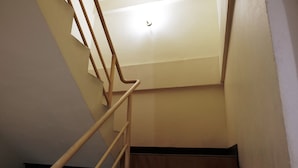 A staircase with wooden handrails and a light fixture on the wall. - Parinya's Apartment (Pattaya)