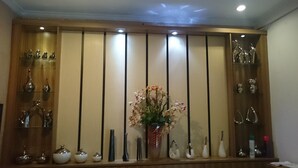 A room with a wooden cabinet displaying various glassware and a central vase with flowers. - Novatel Yogyakarta (Yogyakarta)