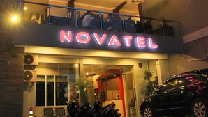 A hotel named "NOVATEL" with a sign, a balcony, and a parked car. - Novatel Yogyakarta (Yogyakarta)