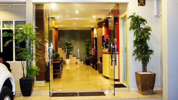 A hotel lobby with a reception desk, a staircase, and potted plants. - Novatel Yogyakarta (Yogyakarta)