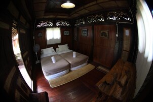 Una habitación tradicional con dos camas, paredes de madera y un ventilador de techo.
