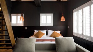 Een moderne slaapkamer met een groot bed, twee nachtkastjes, een bank en een trap.