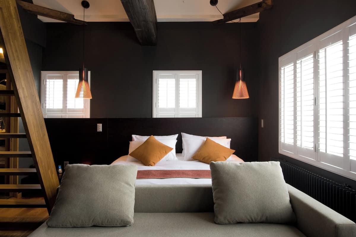 Un dormitorio moderno con una cama grande, dos mesitas de noche, un sofá y una escalera.