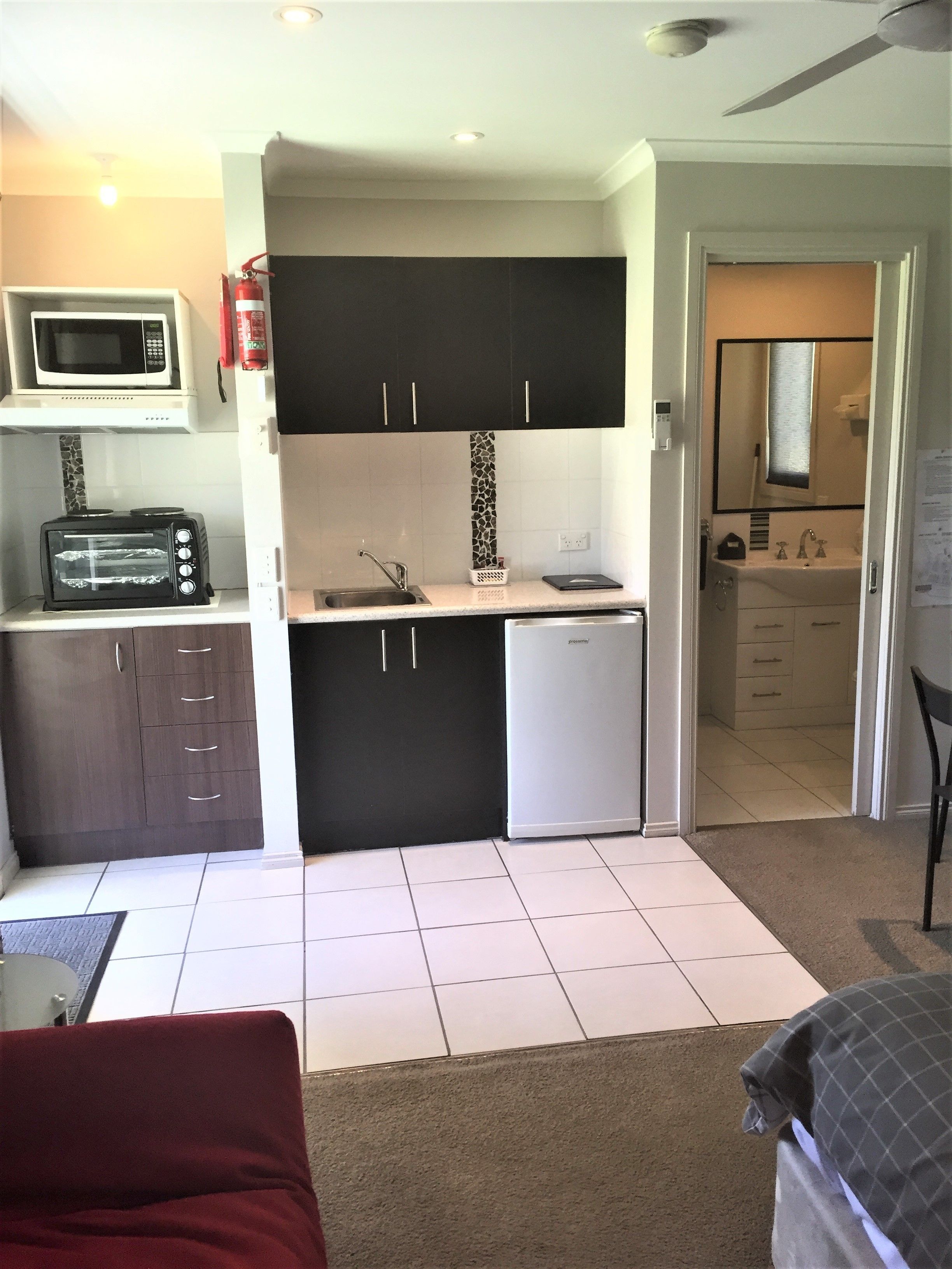 A compact kitchen with a microwave, toaster, sink, and a small refrigerator.