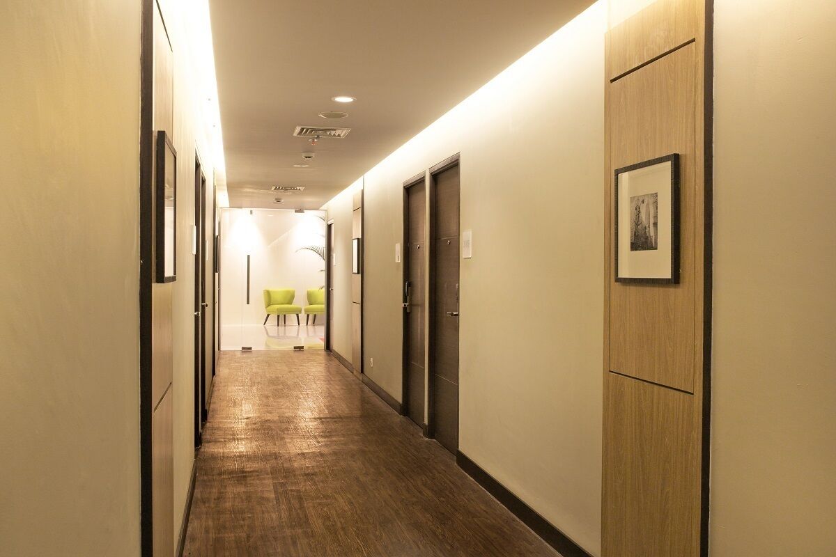 Un couloir d’hôtel avec un plancher en bois, des portes et un tableau encadré accroché au mur.