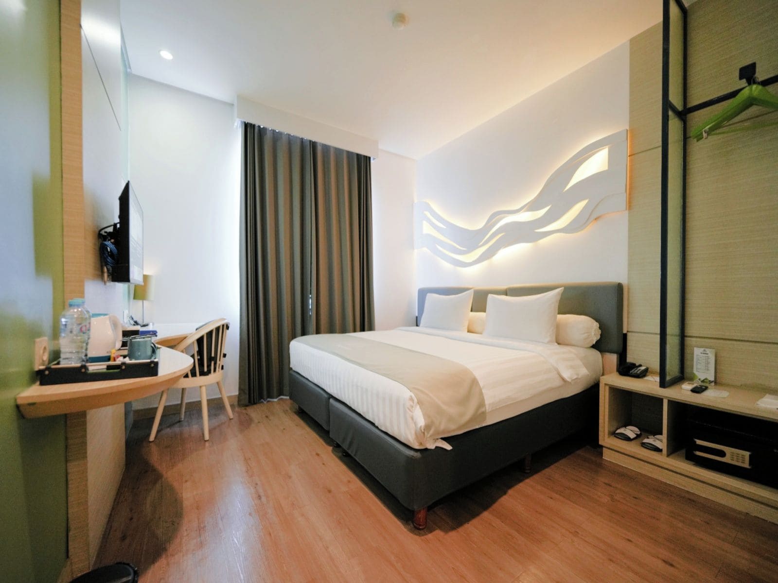 Una habitación de hotel con cama, escritorio, silla, televisión y espejo.