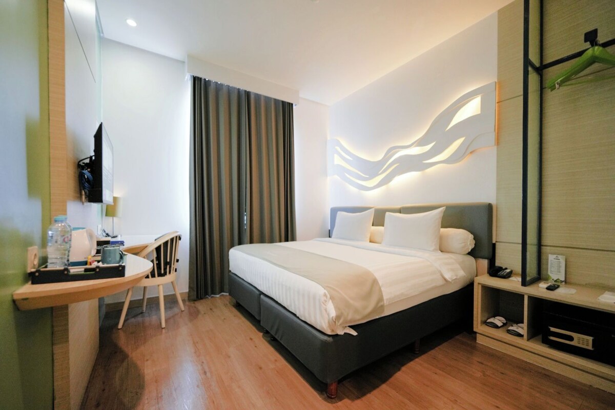 Une chambre d’hôtel comprenant un lit, un bureau, une chaise, une télévision et un miroir.