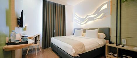 Una habitación de hotel con cama, escritorio, silla, televisión y espejo.
