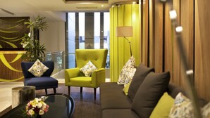 Un hall moderno con un sofá, sillones, una mesa de centro y una lámpara.