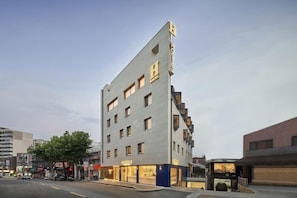 A modern hostel building with multiple floors, large windows, and a prominent sign on the facade. - Itaewon Inn (Seoul)