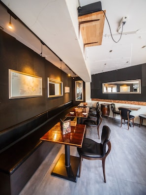 A restaurant interior with a long counter, multiple tables, and chairs. - Itaewon Inn (Seoul)