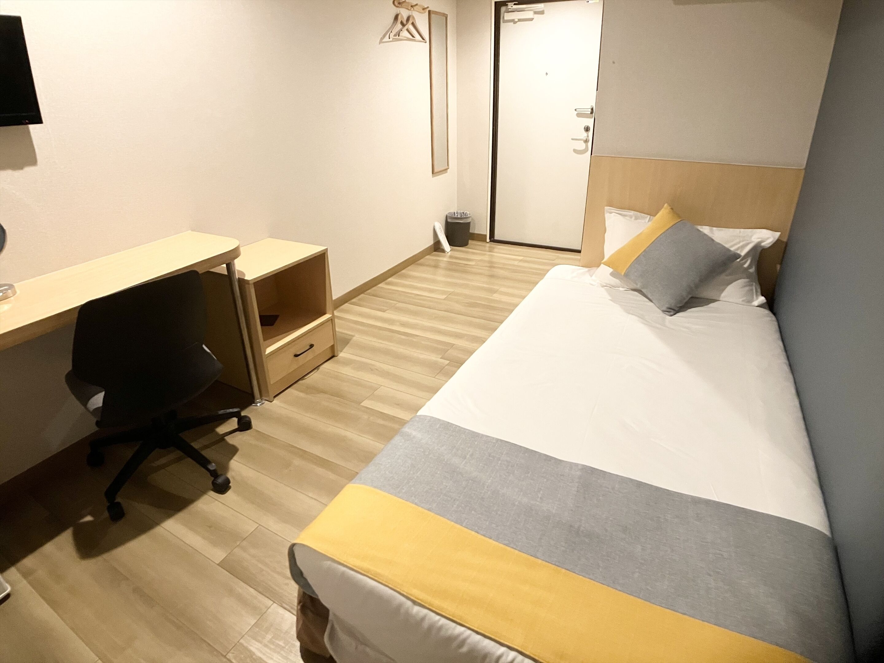 Una habitación de hotel con cama, escritorio, silla y armario.