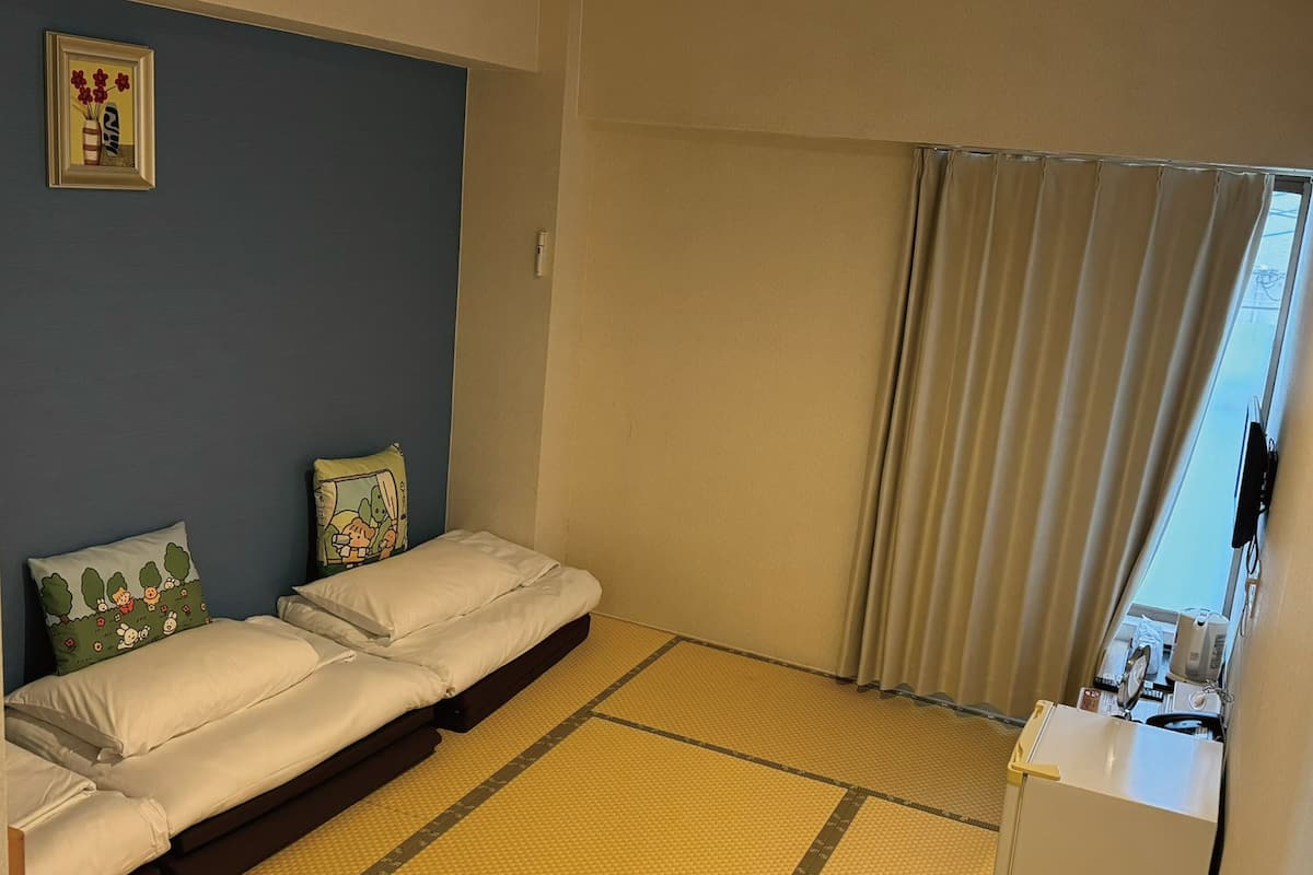 A room with a bed, a small desk, and a window with curtains.