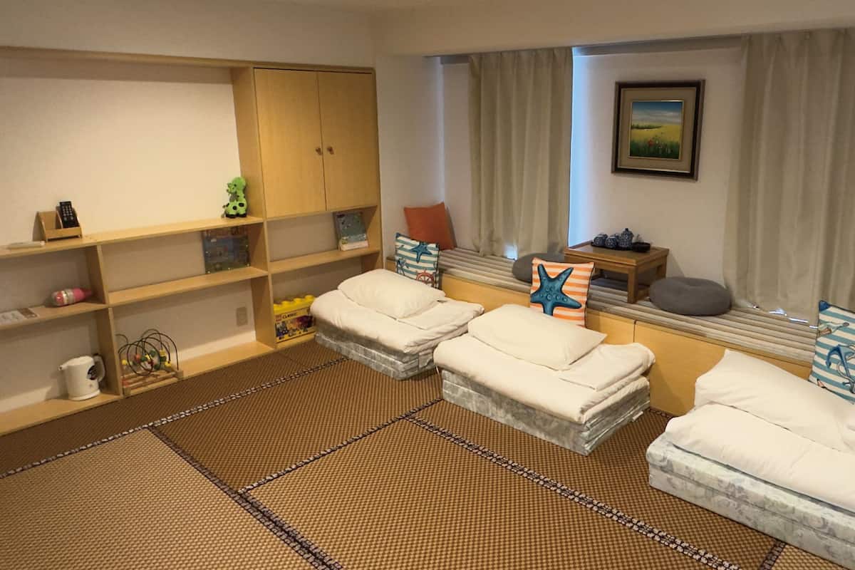 A cozy room with a bed, a shelf with toys, and a window with curtains.