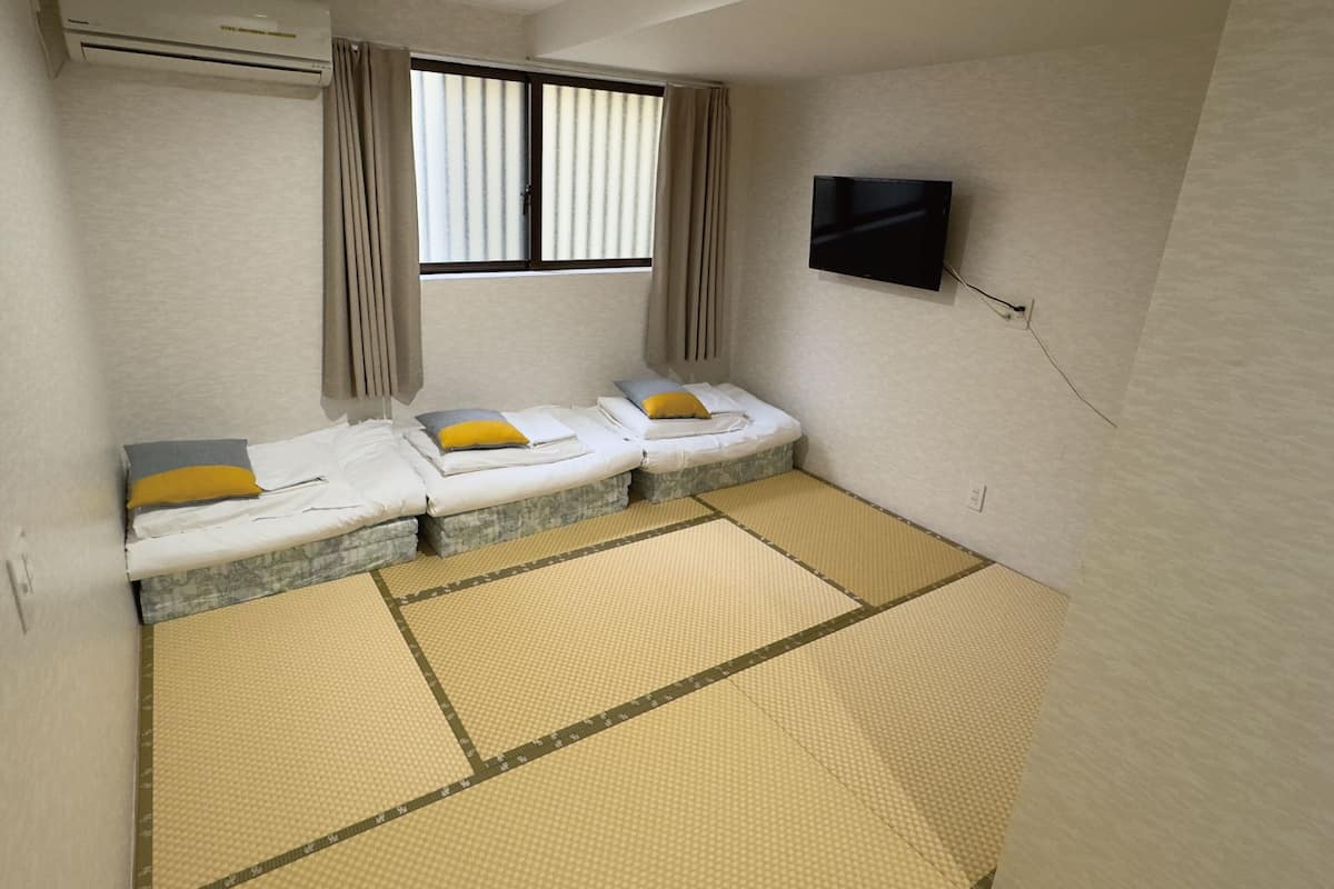 A room with two beds, a TV, and a window with curtains.