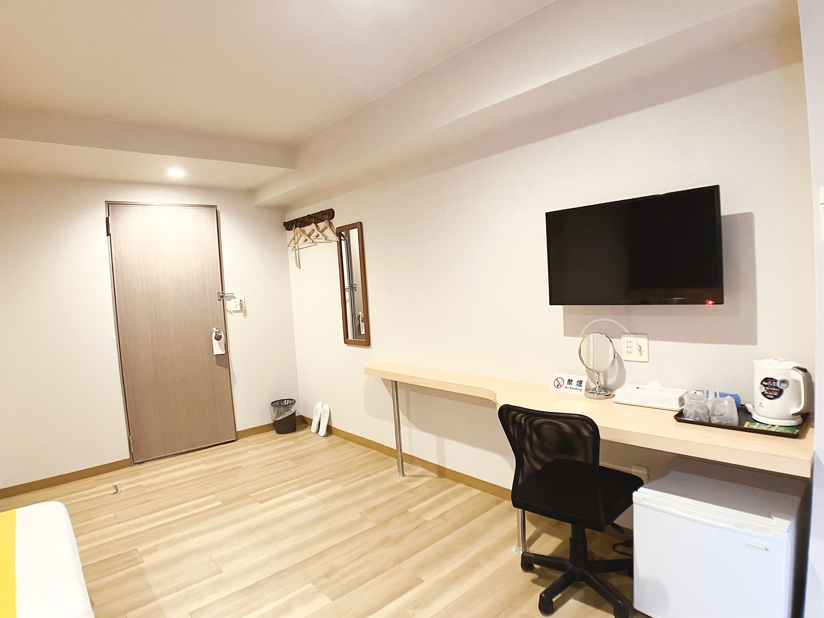 Un petit bureau comprenant un bureau, une chaise, un téléviseur et un réfrigérateur.
